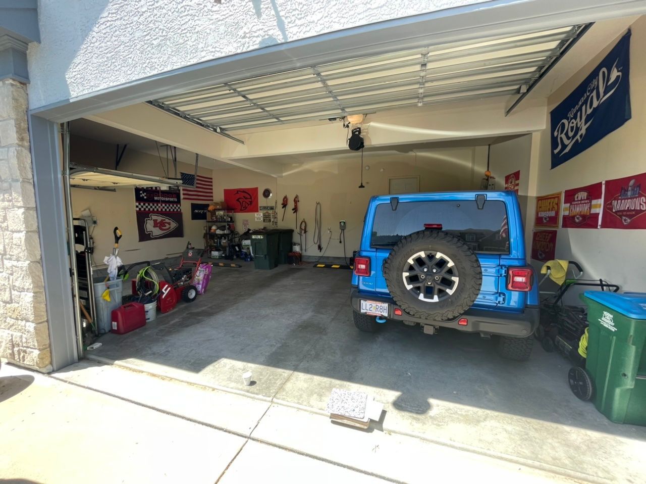 A blue jeep is parked in a garage with the door open.