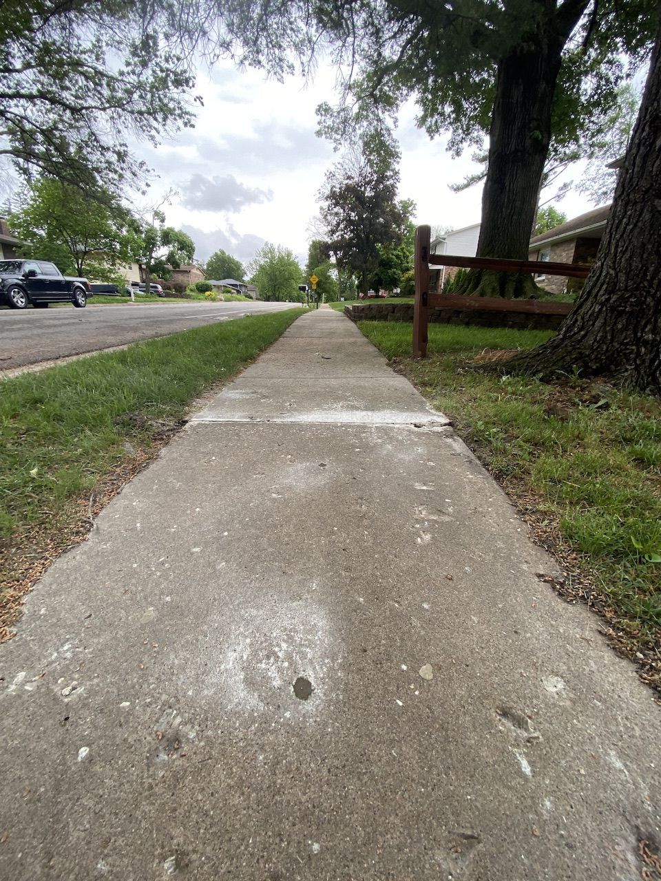 A sidewalk with a wooden fence on the side of it