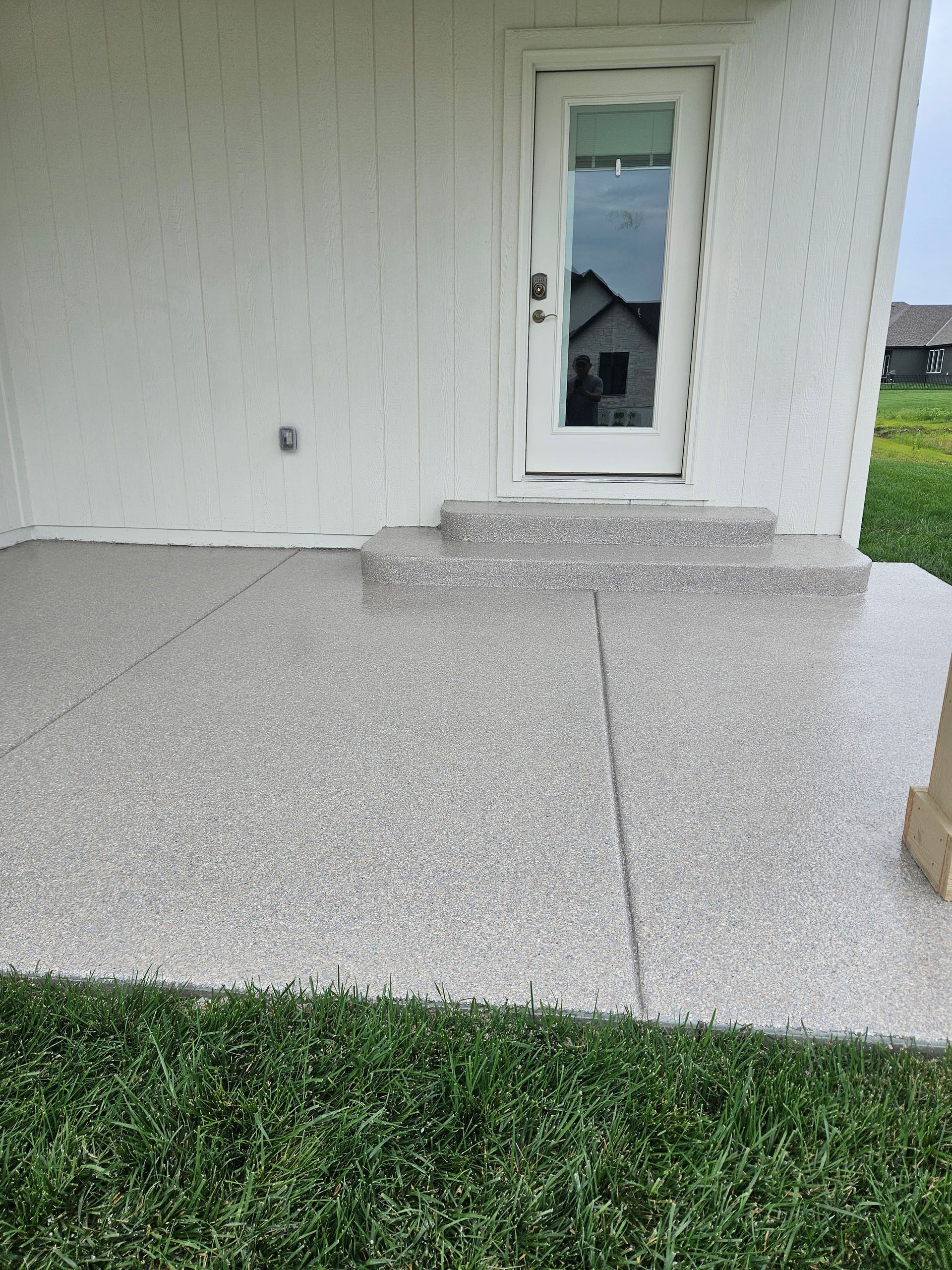 A white house with a concrete patio and steps leading to it.