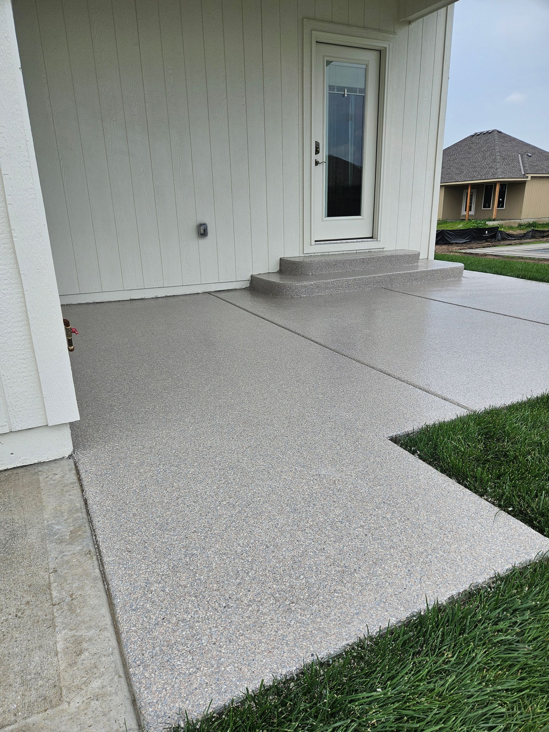 A concrete walkway leading to the front door of a house.