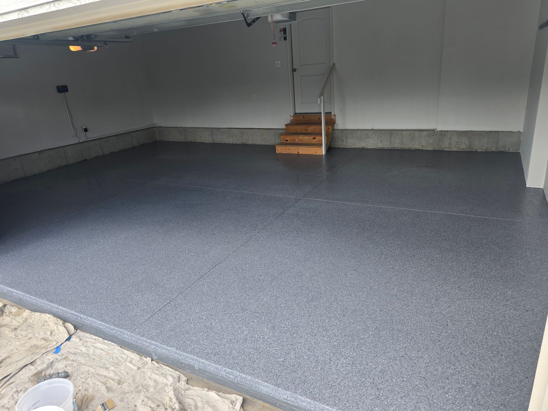 A garage with a gray floor and stairs leading up to it.