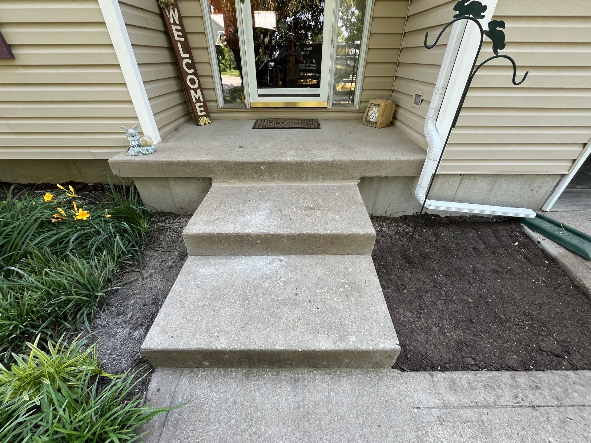 A set of concrete steps leading up to the front door of a house.