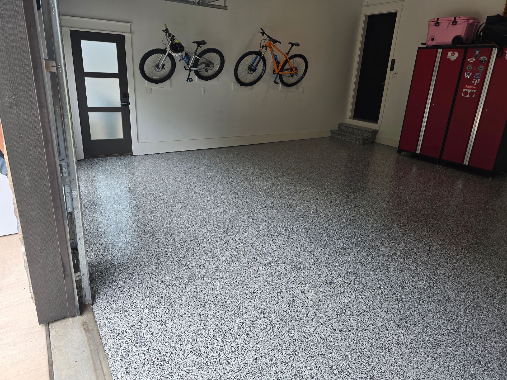 A garage with bikes hanging on the wall and a gray floor.