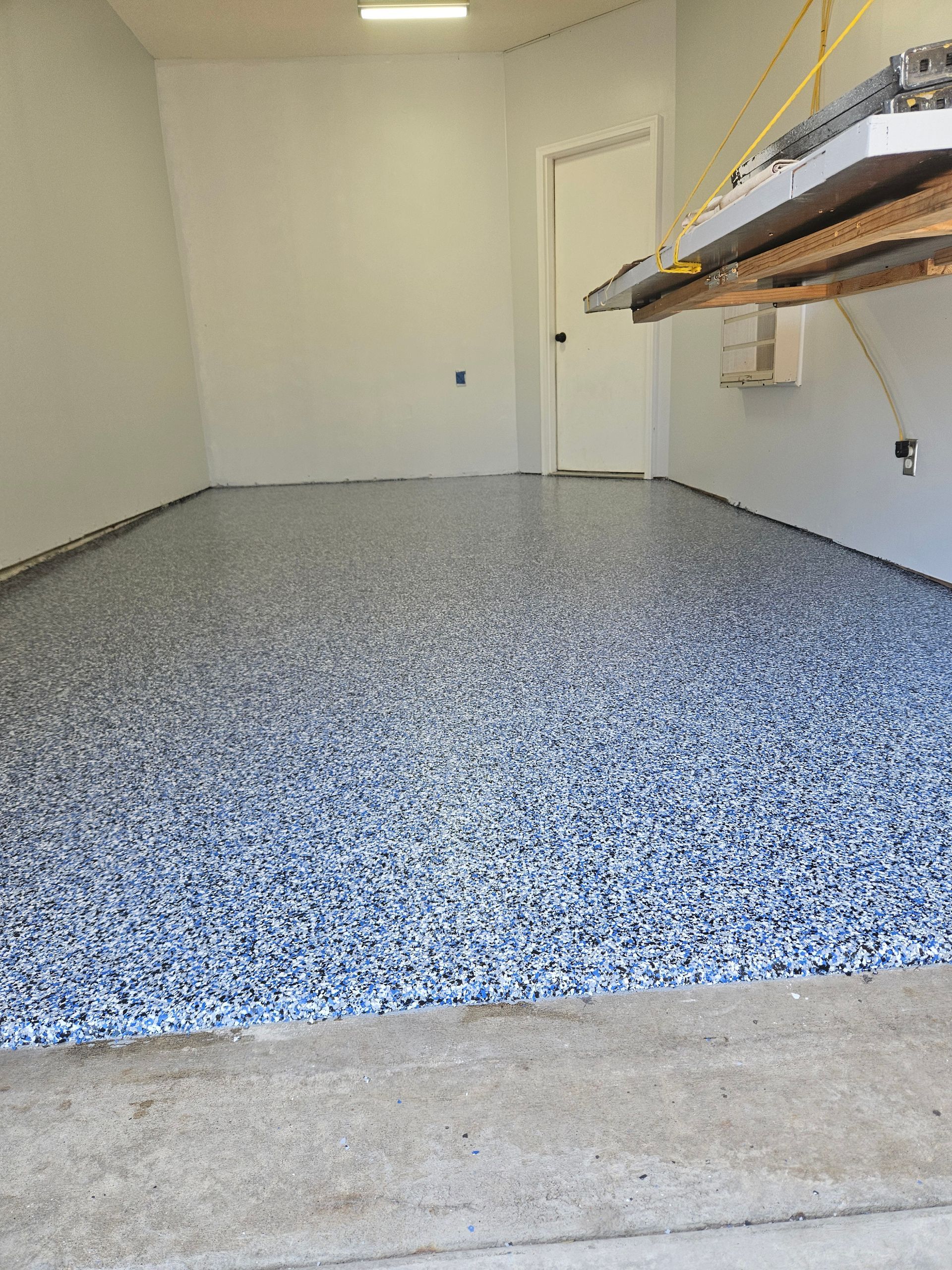 A garage with a concrete floor and a shelf on the wall.
