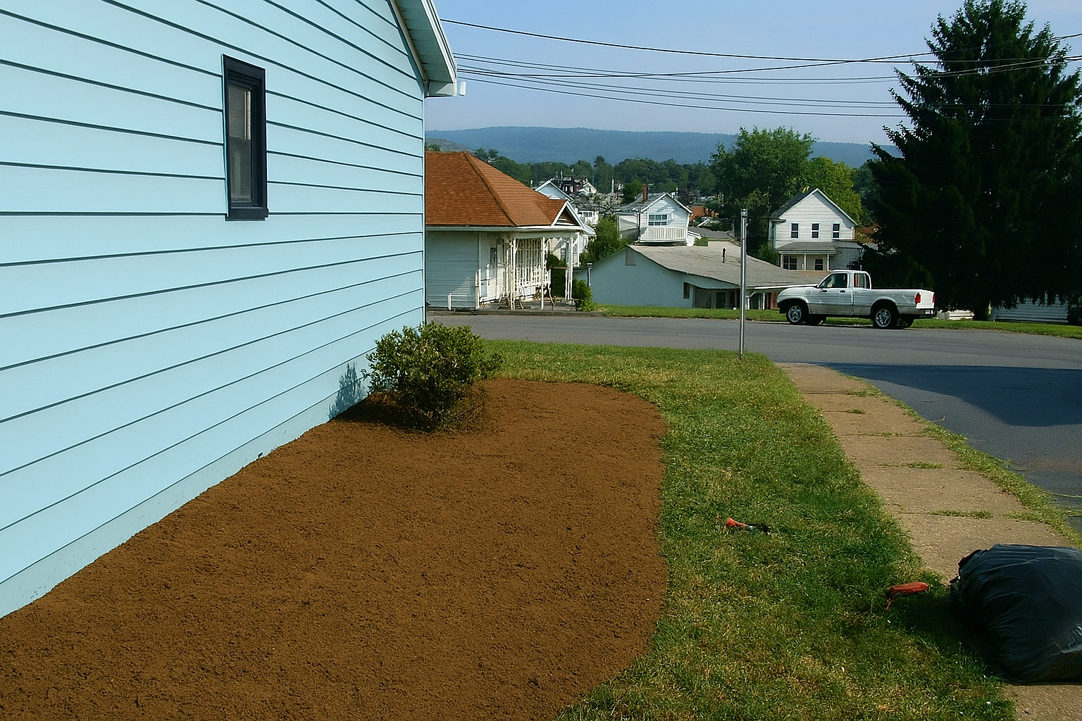 A hanging chair with a yellow pillow is sitting on a wooden deck.