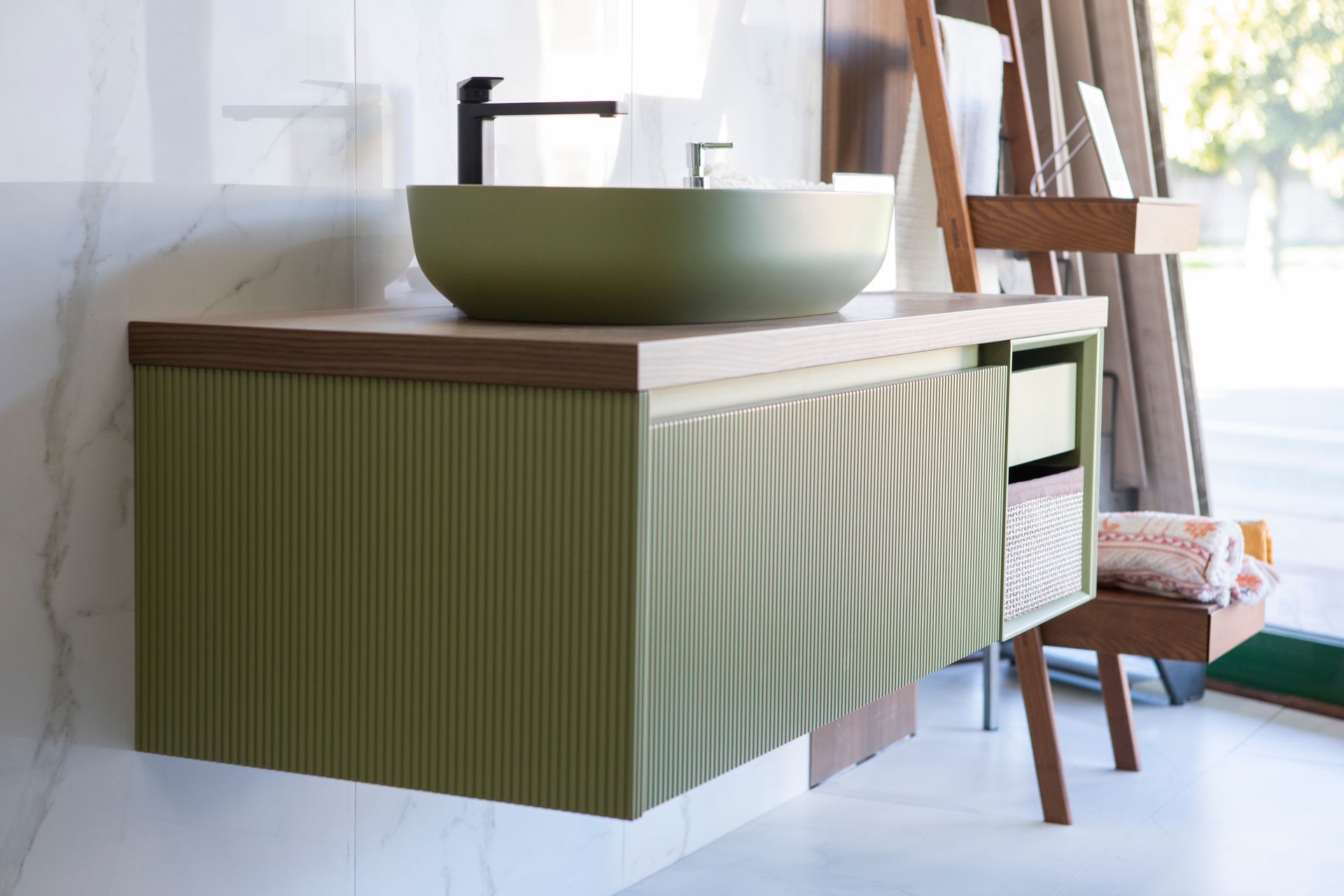 Mobile bagno verde con lavabo a appoggio, piano in legno e frontale scanalato.