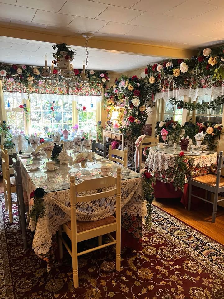 Dining room lavishly decorated with flowers. Table set for a meal, ornate chandelier, and floral garlands cascade throughout.