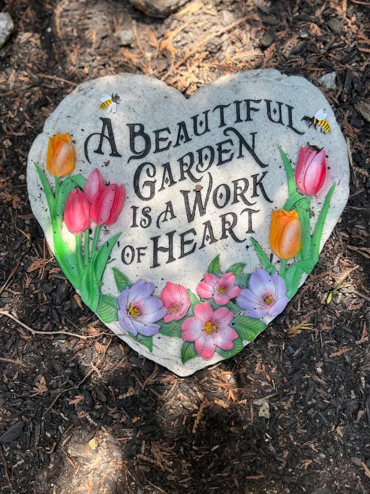 Heart-shaped garden stone with colorful painted flowers and the text.
