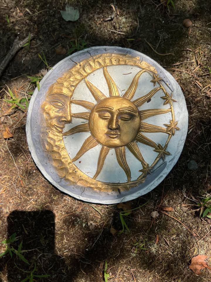 Round, decorative garden stepping stone with a gold sun and moon design. The sun is in the center and the moon is on the left side.