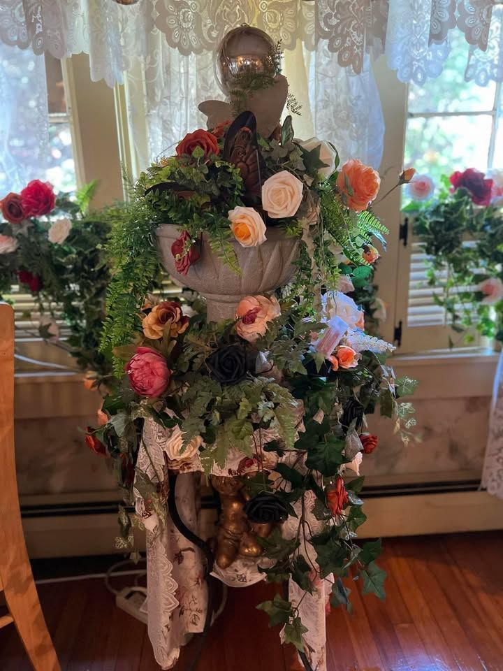 Floral arrangement on pedestal table with flowers and greenery.