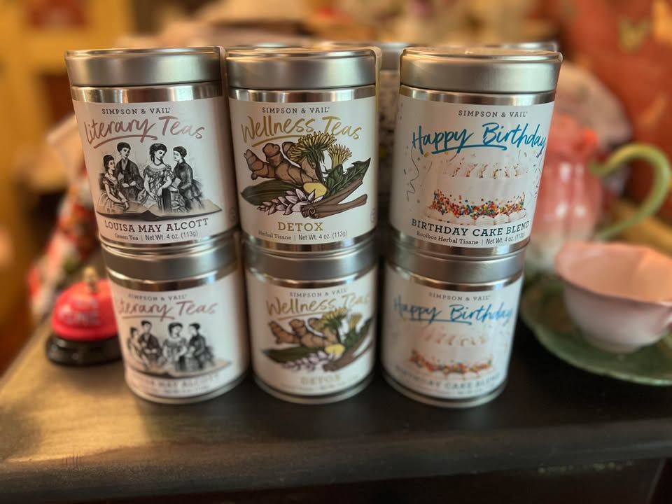 Six silver-lidded tea tins stacked in two rows. Each tin features a different label. Six silver-lidded tea tins stacked in two rows. Each tin features a different label.