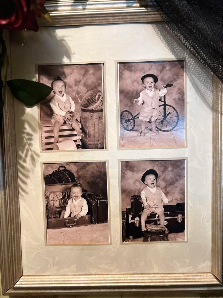 A framed collage of four vintage-style photos of a baby wearing a vest and hat, posed with a tricycle, trunks, and a barrel.