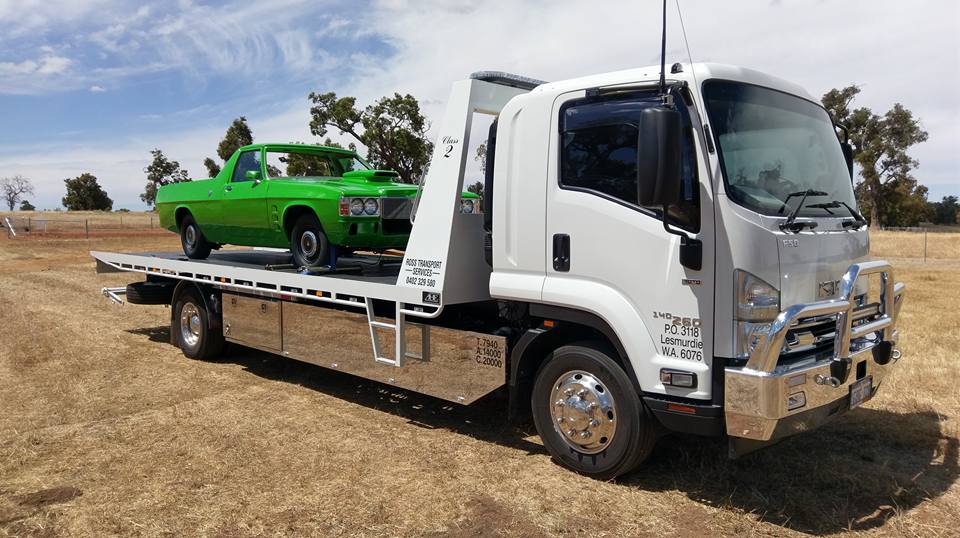 green colour car on a flat bed transportation truck