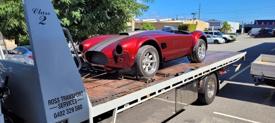 front view of a red cars on a tow truck for transportation