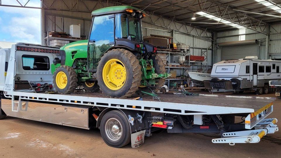 side view of a tractor on a flat bed tow truck