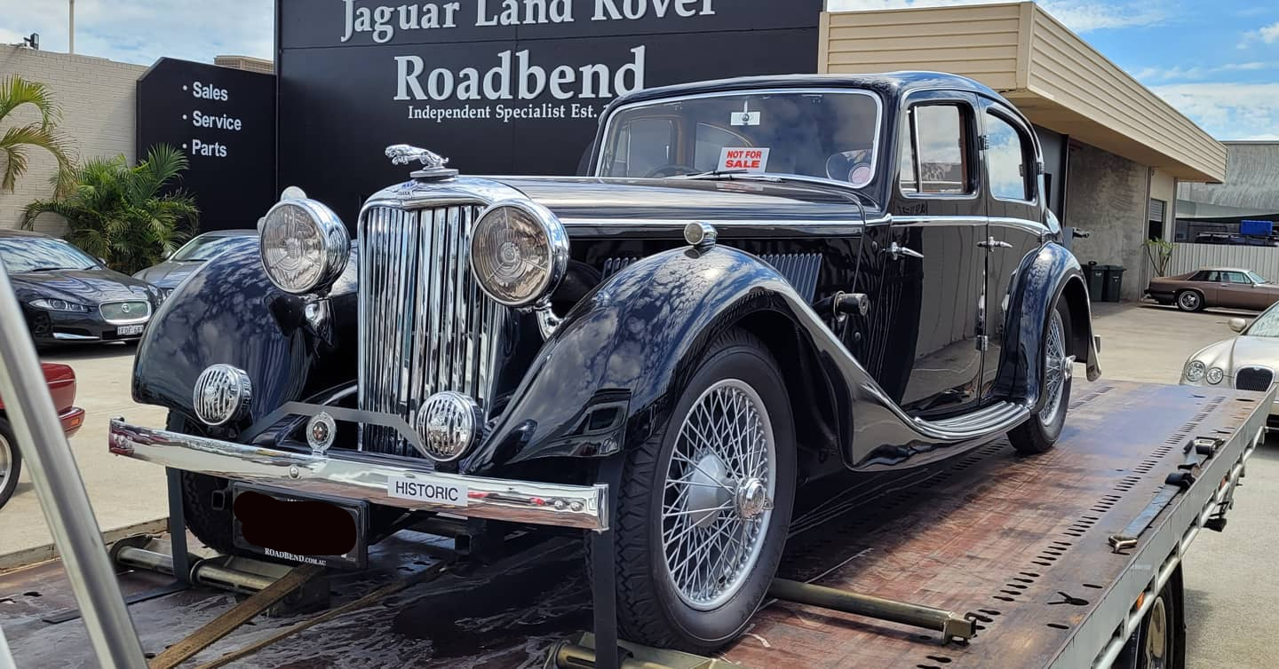 front view of an old classic black car being transported