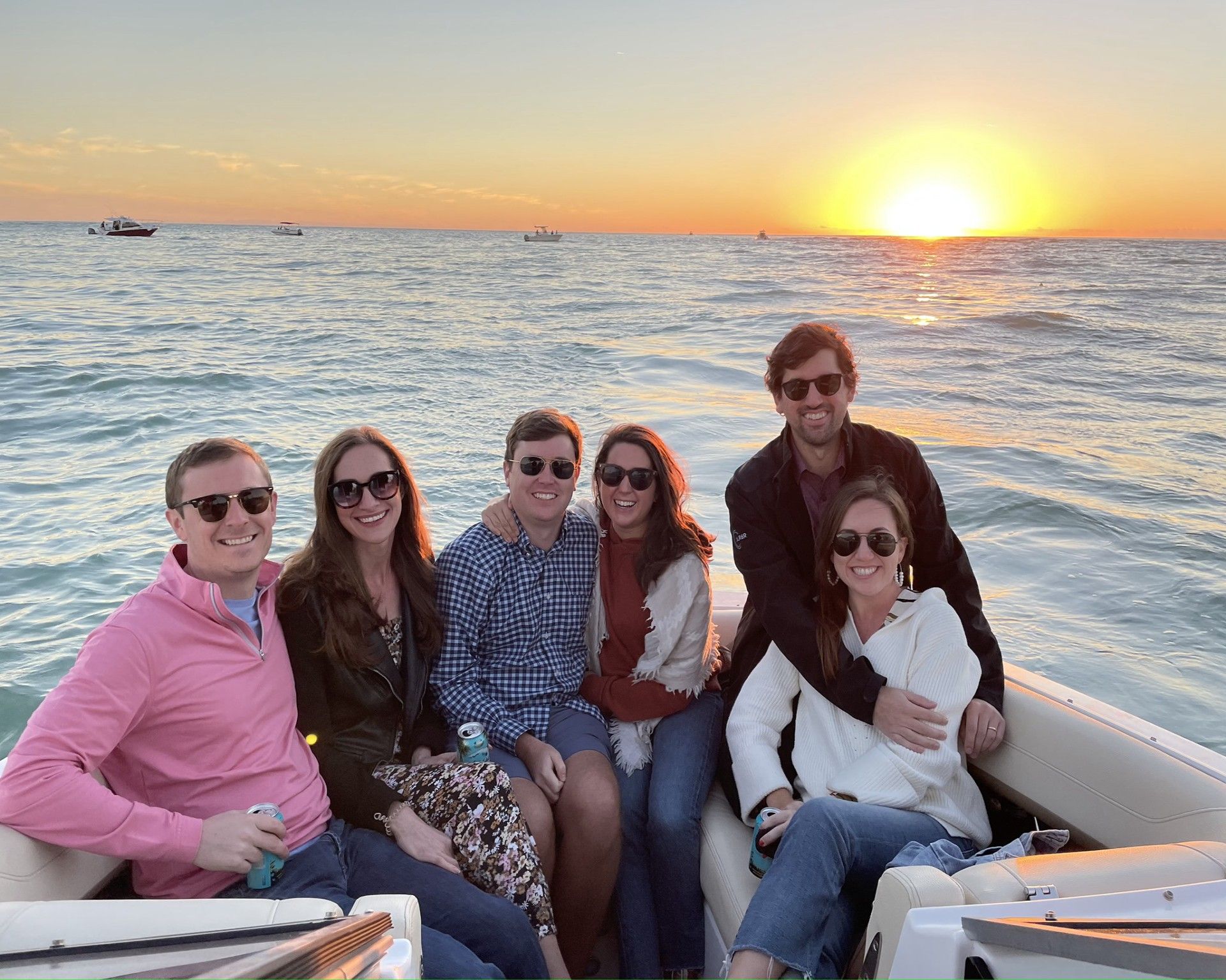 A group of smiling people wearing sunglasses in the back of a boat