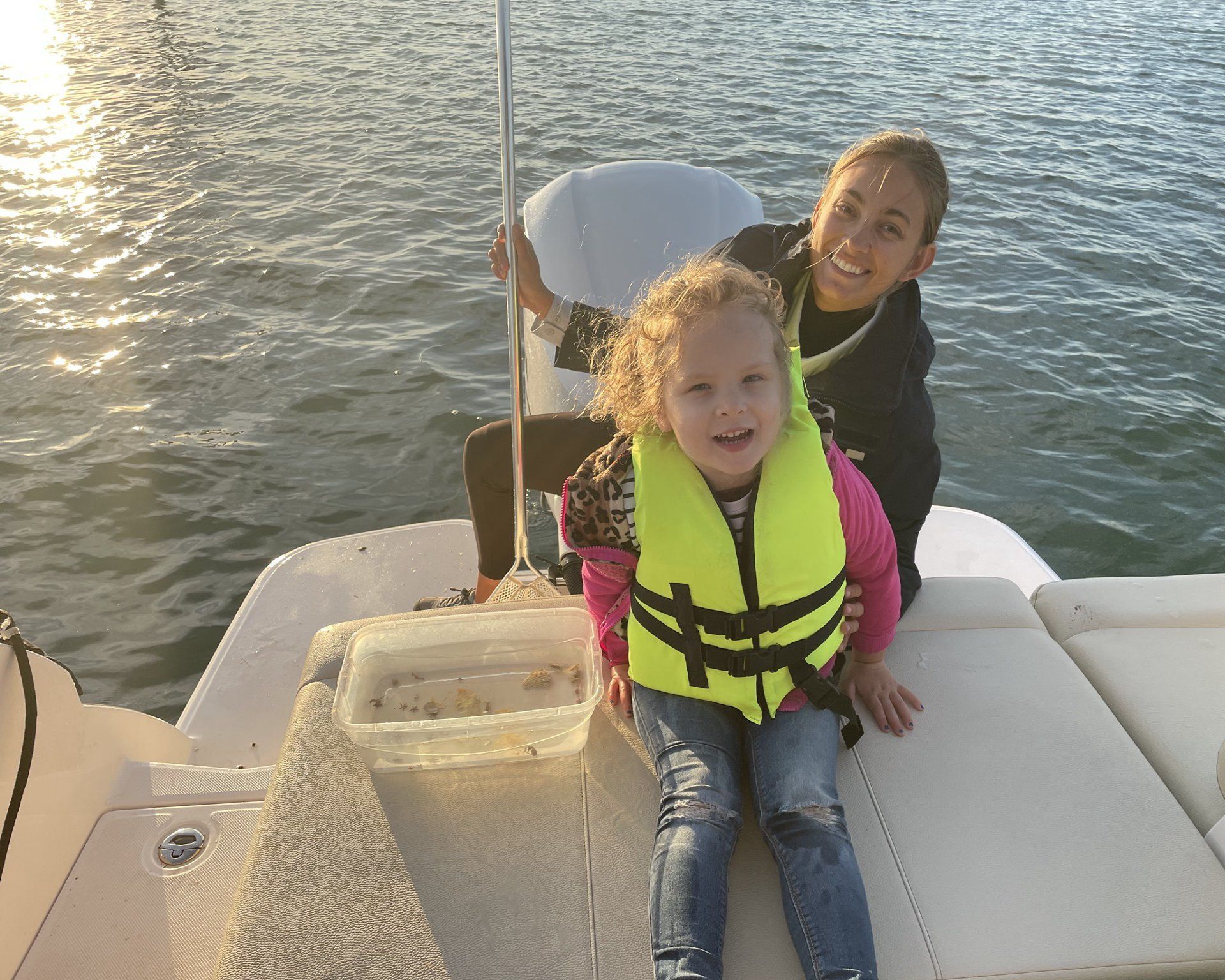 A woman and a little girl are sitting on the back of a boat.