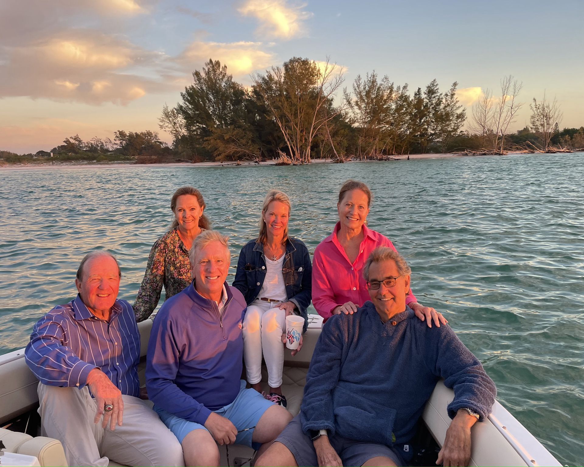 A smiling group of people in a boat at sunset