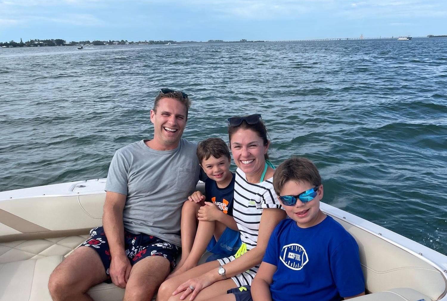 A family smiles in the back of a boat