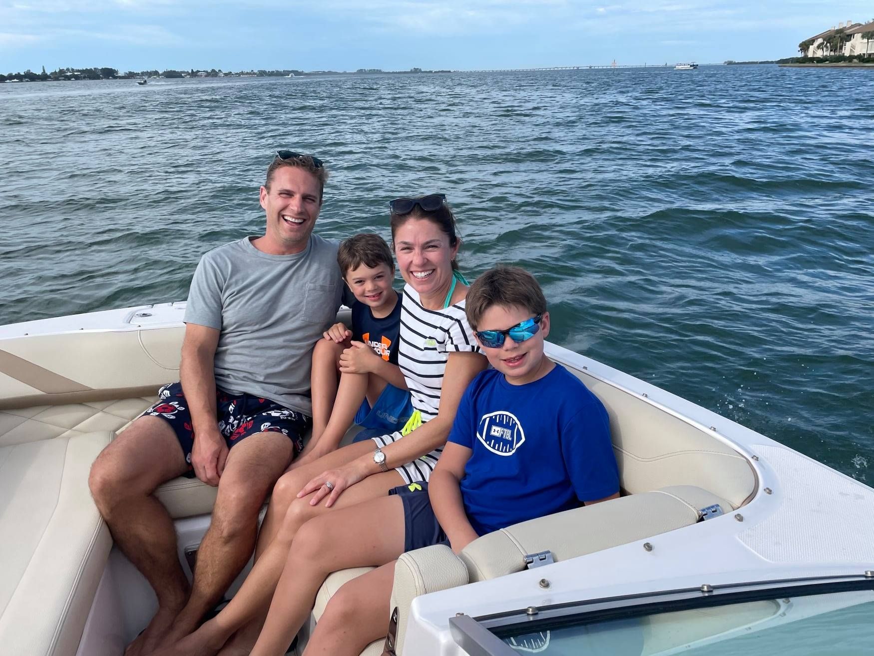 Four people smiling in the back of a boat and enjoying water activities around Anna Maria Island