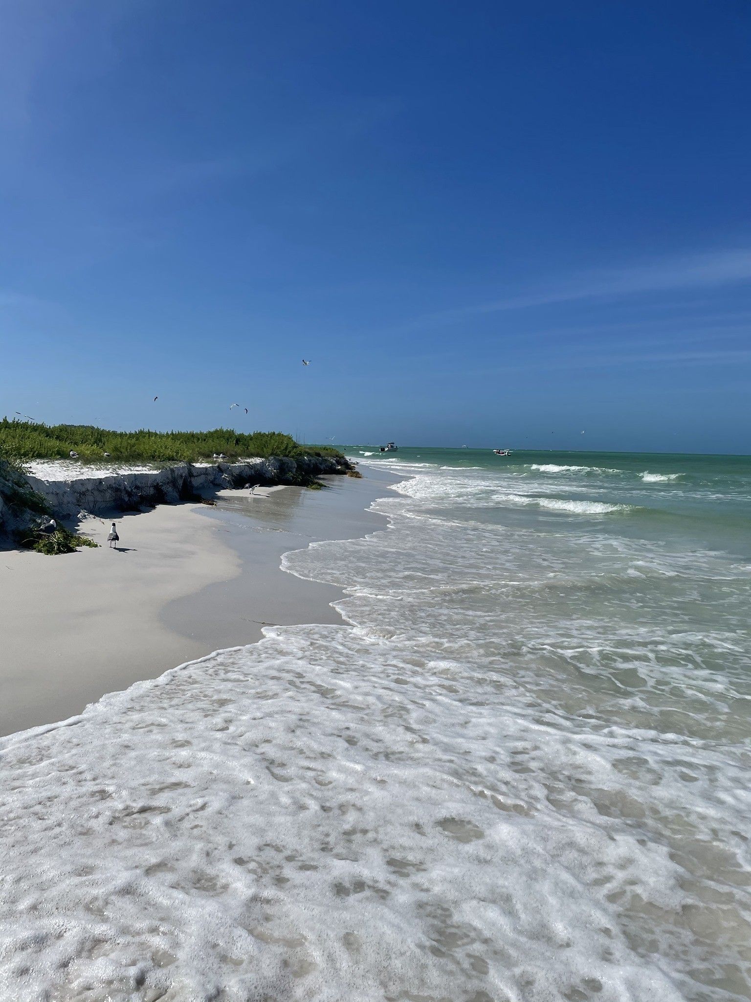 ocean water crashing onto the white sand