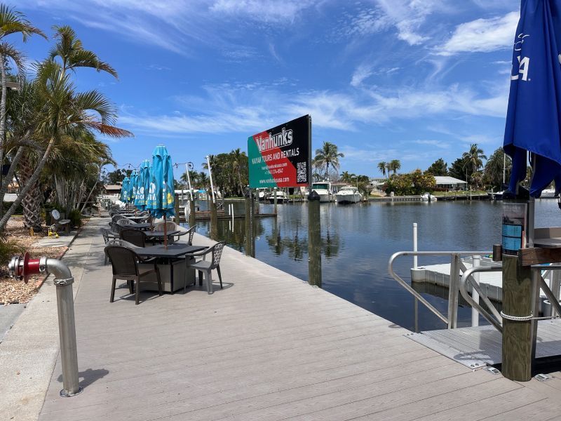 Waterfront outdoor seating area; tables with umbrellas overlooking a canal.