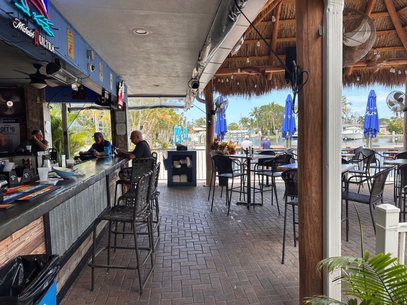 Outdoor bar with thatched roof and seating area.
