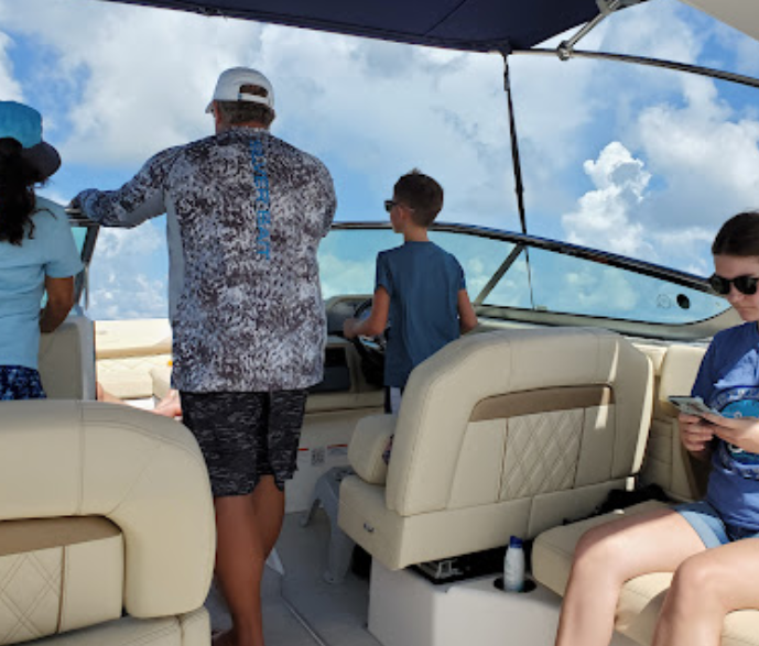 A group of people are on a boat and one of them is looking at her phone