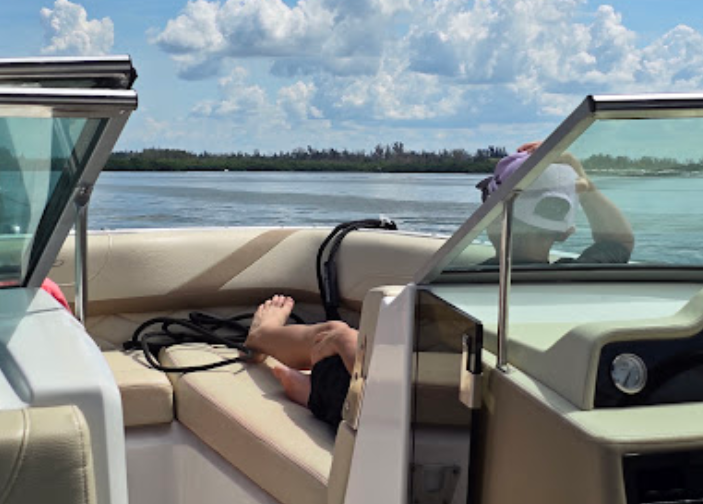 A person laying on the back of a boat in the water