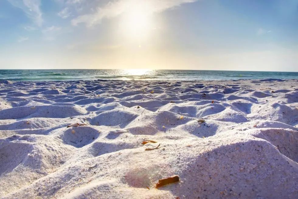 A sandy beach with a sunset in the background and a pile of sand in the foreground.