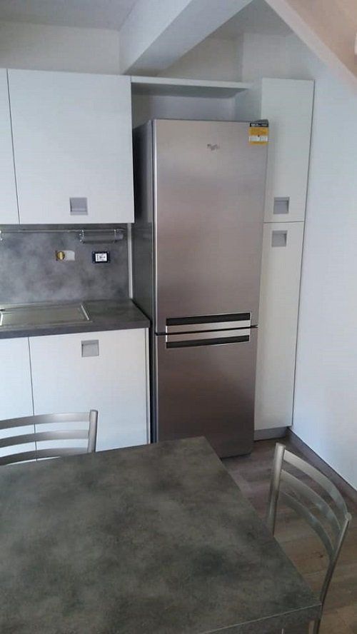 Dettaglio di una cucina, frigo, tavolo e pensili