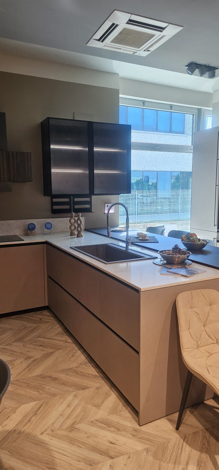 Cucina moderna con isola, lavello, mobili neri e ampia finestra con vista sull'acqua e sugli edifici.