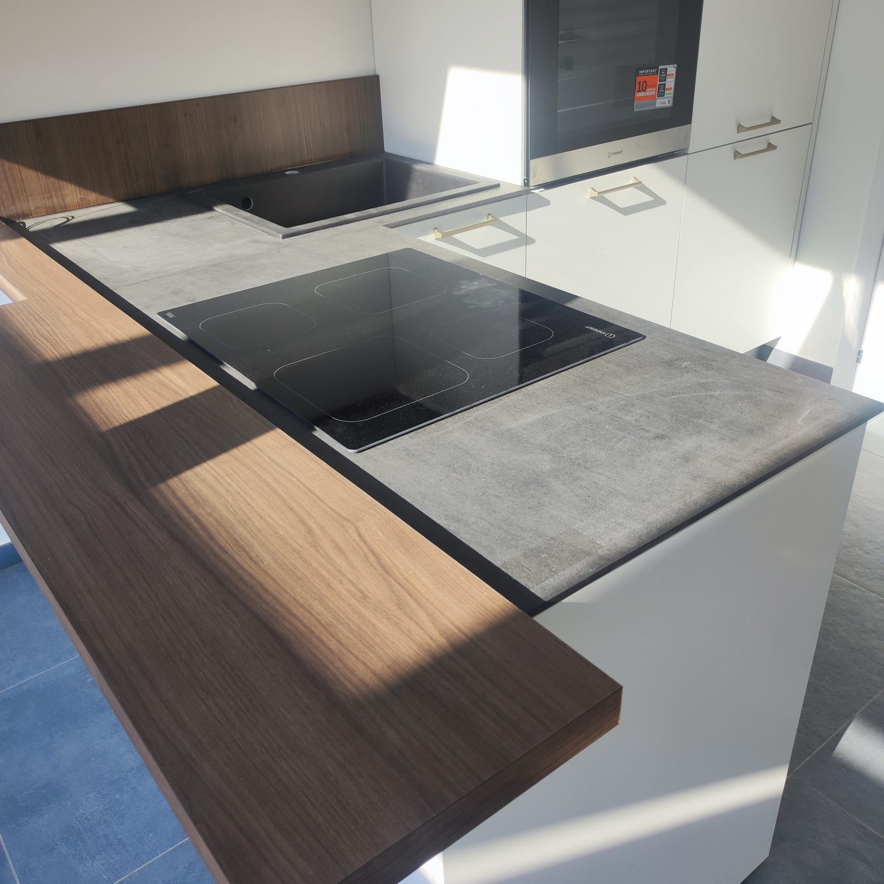 Cucina moderna con mobili scuri, forno a incasso e panca sotto la finestra in una stanza luminosa