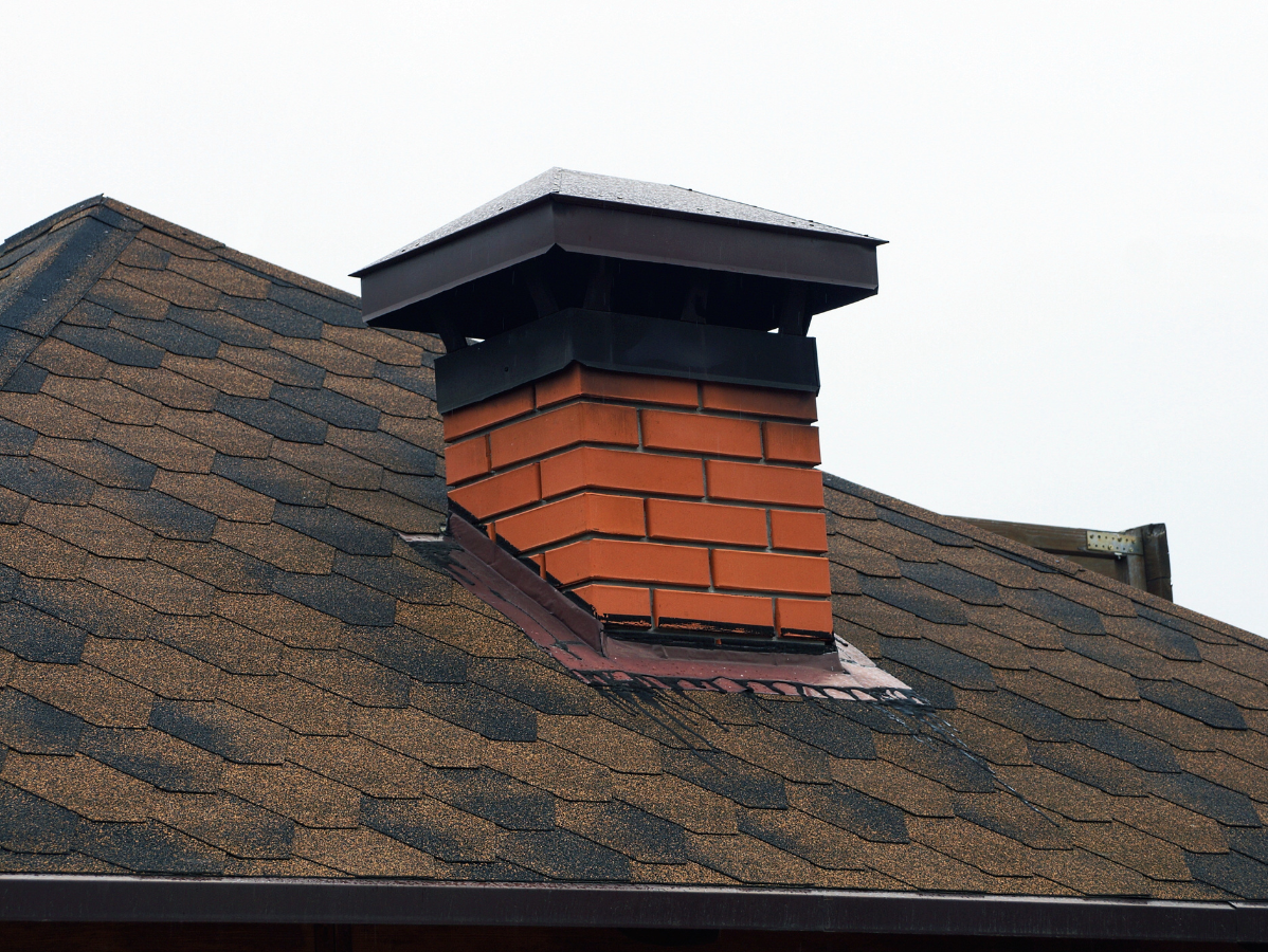 Brick chimney on a brown shingle roof.