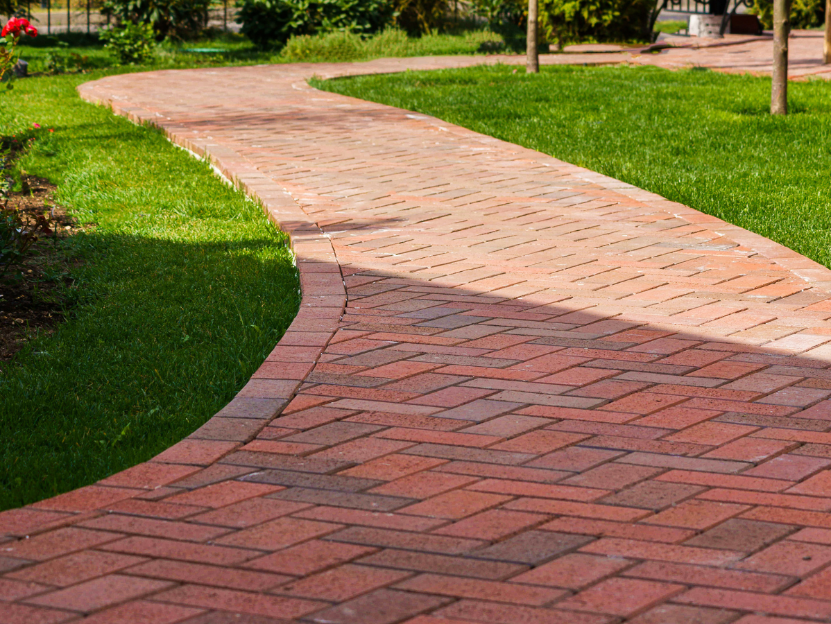 Brick pathway winding through green grass.
