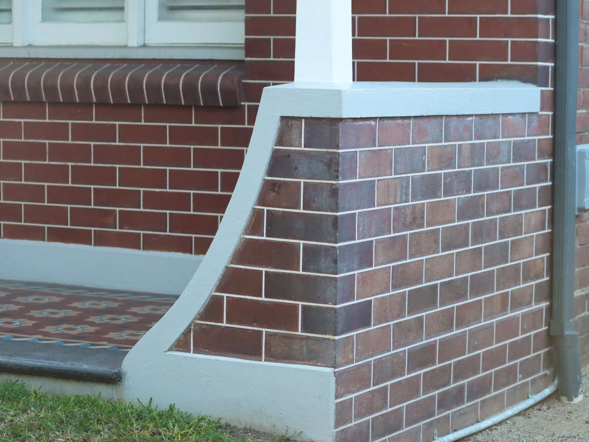 Brick column with gray accents and a white pillar, part of a building's exterior.