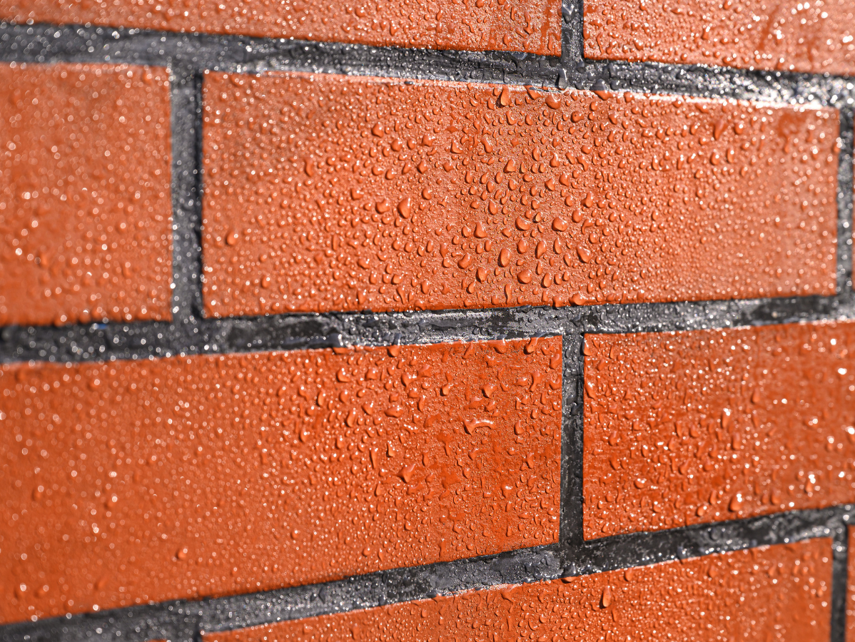 Wet red brick wall, close-up showing water droplets.