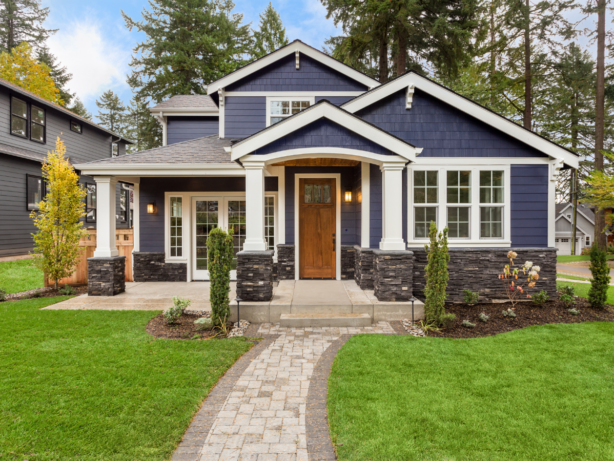 Blue house with white trim, brick pathway, and green lawn.