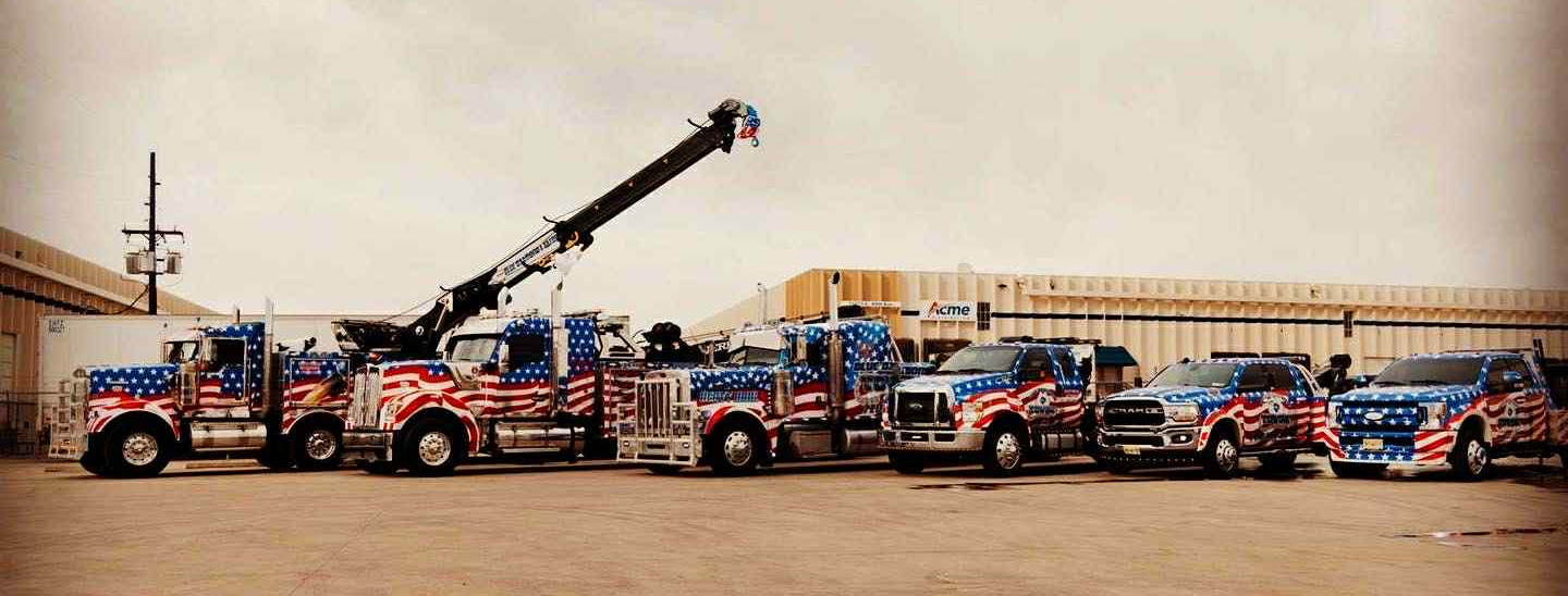 Several tow trucks and service vehicles with an American flag theme are parked outside.