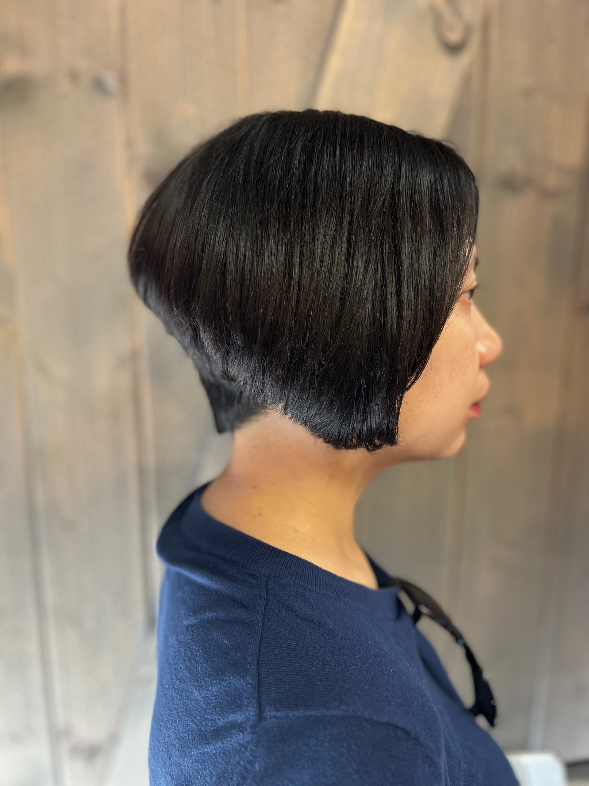Woman with a short, black, stacked bob haircut; wearing a blue shirt.