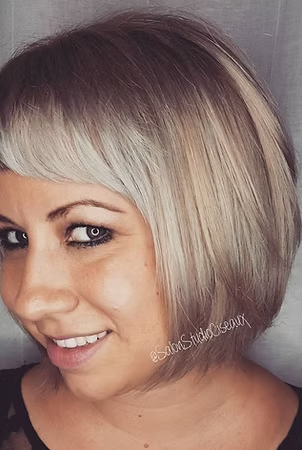 Woman with short, layered, ash blonde bob haircut, smiling, looking at the camera.