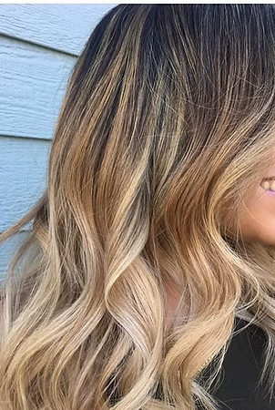 Ombre hairstyle with dark roots fading into golden blonde waves.