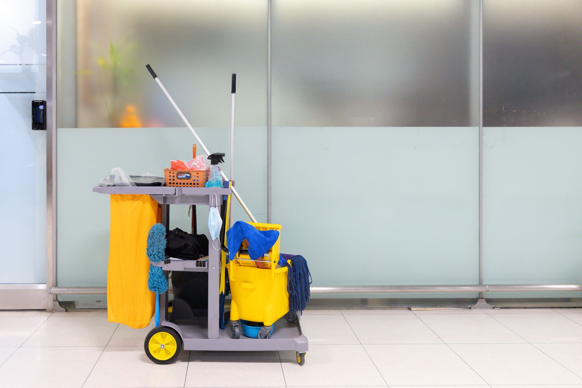 A cleaning cart with a mop , bucket , sponge and other cleaning supplies.