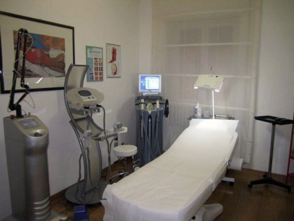 Ambulatorio medico con tavolo per visite, macchine laser e altre attrezzature.