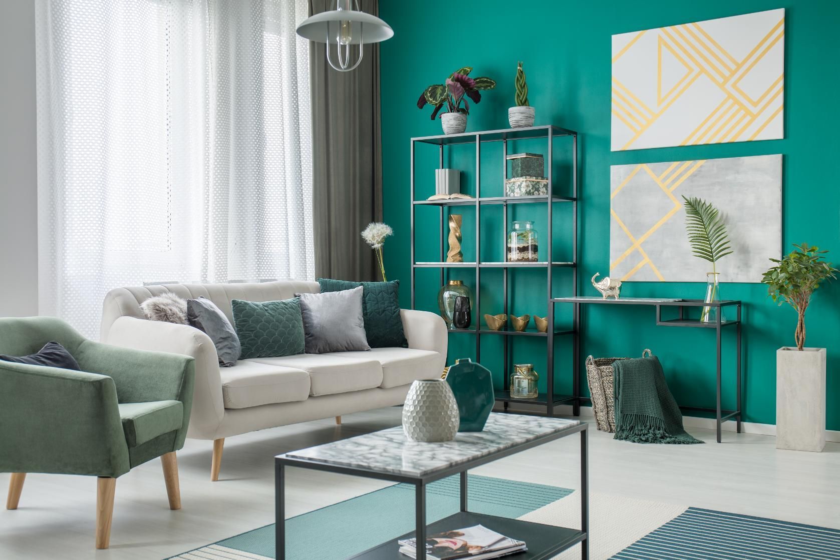 A living room with green walls, a white couch, a chair, a coffee table and a bookshelf.