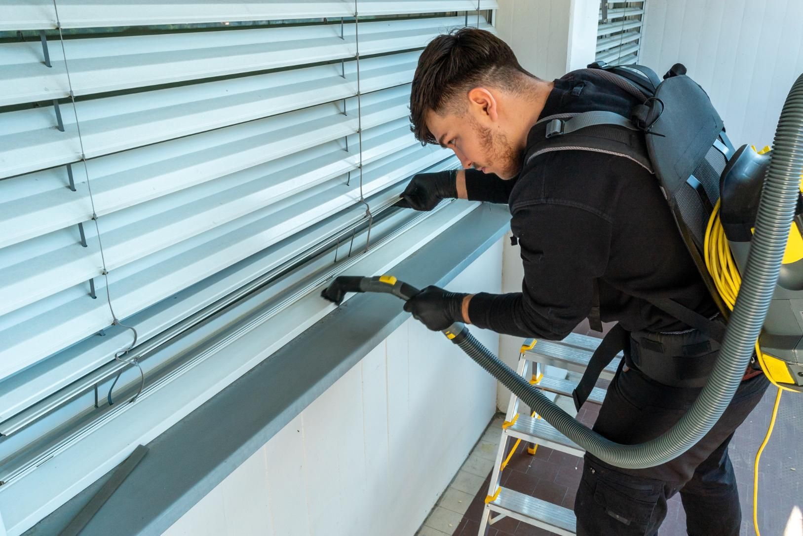A man is cleaning a window with a vacuum cleaner.