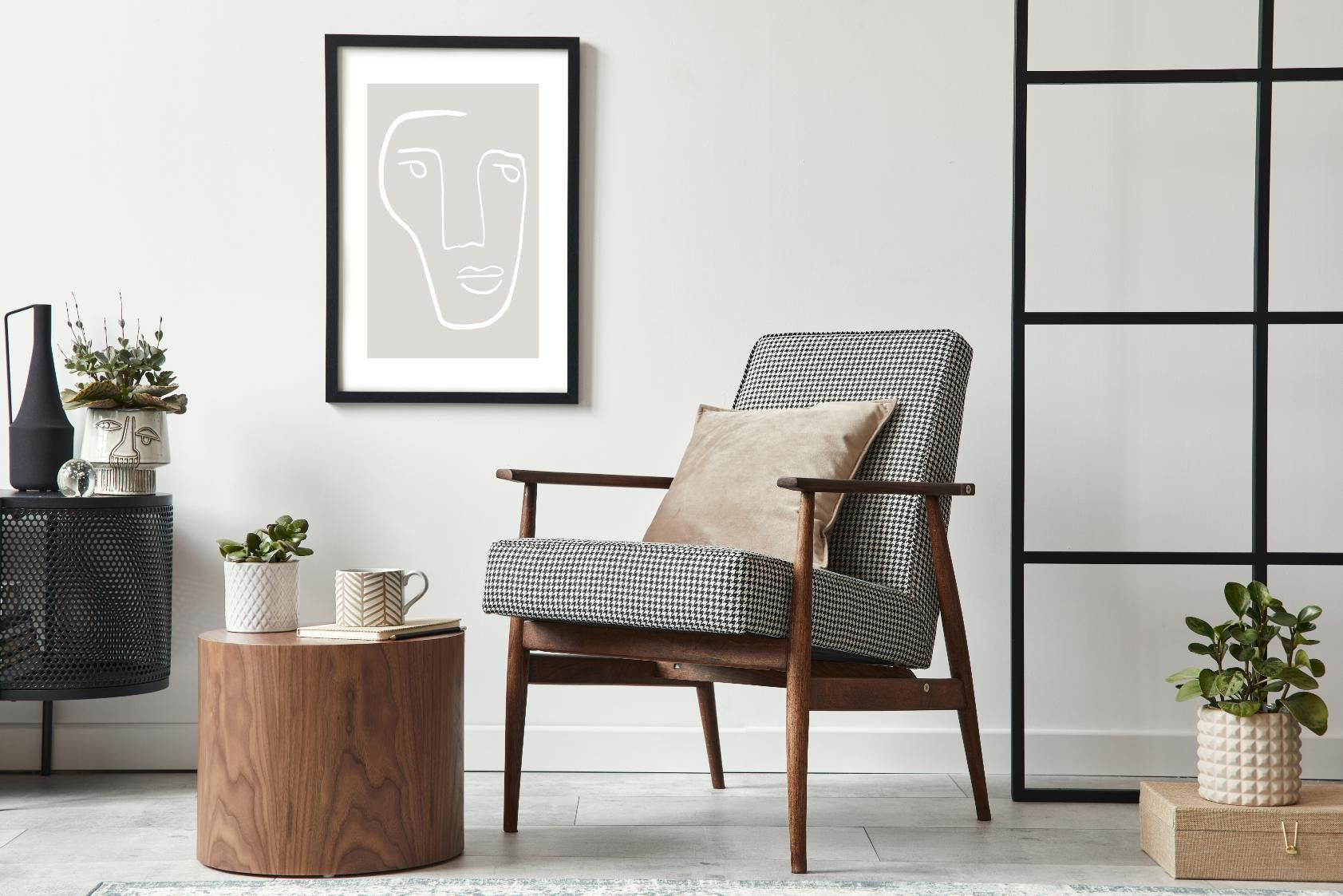 A living room with a chair, table, and a picture on the wall.
