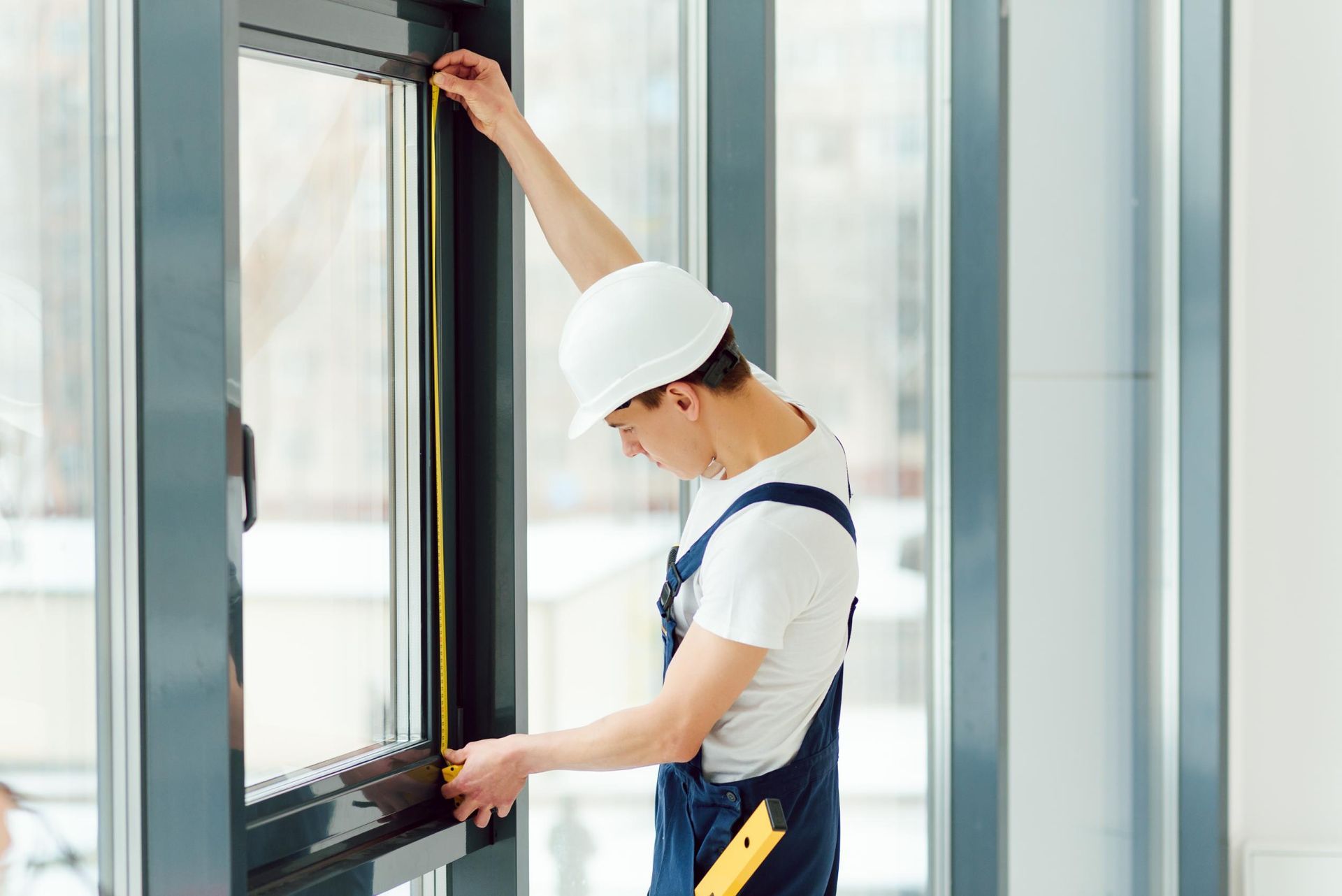 A man is measuring a window with a tape measure.