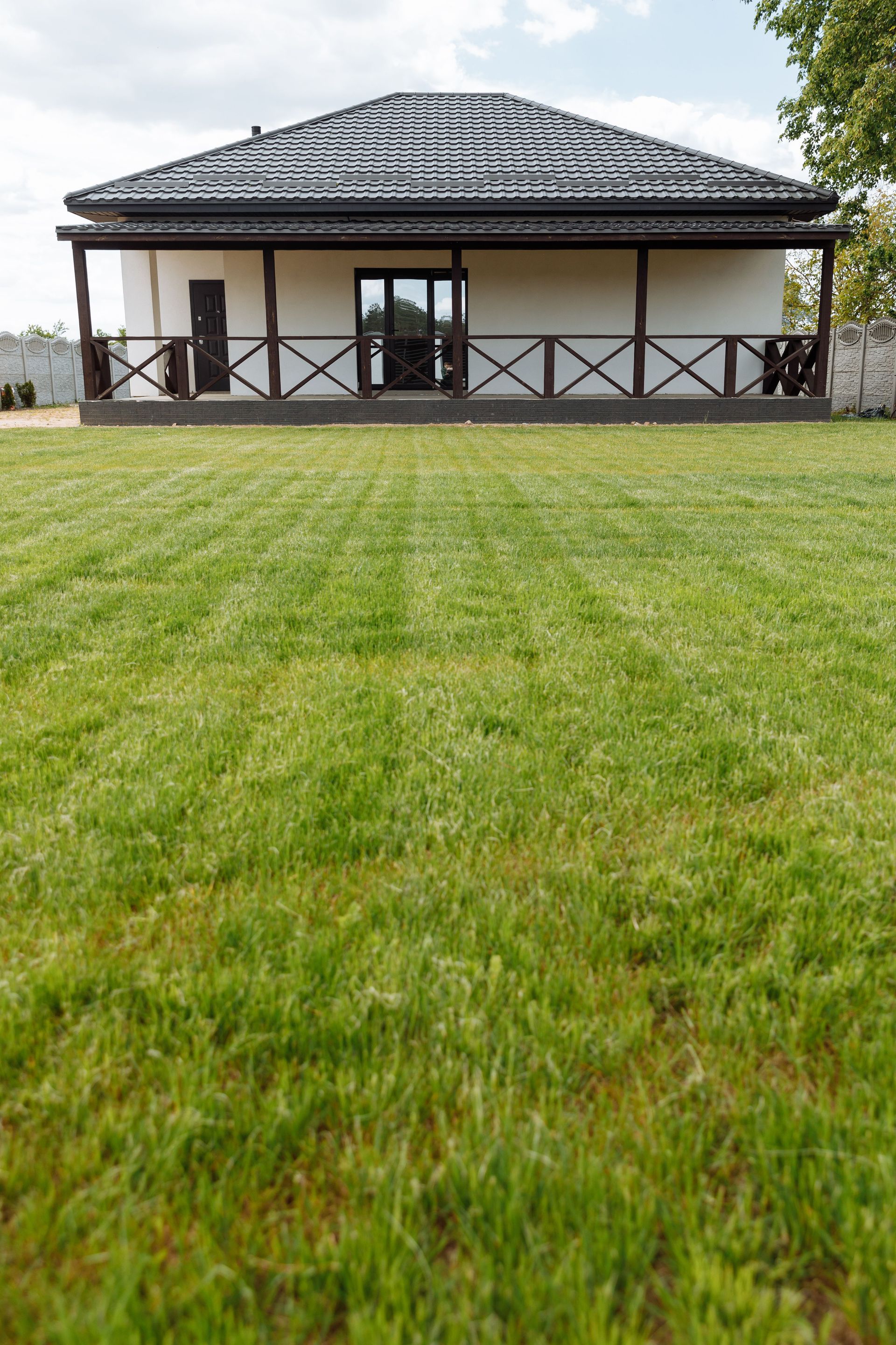 Single-story house with a dark tiled roof and large green lawn in front